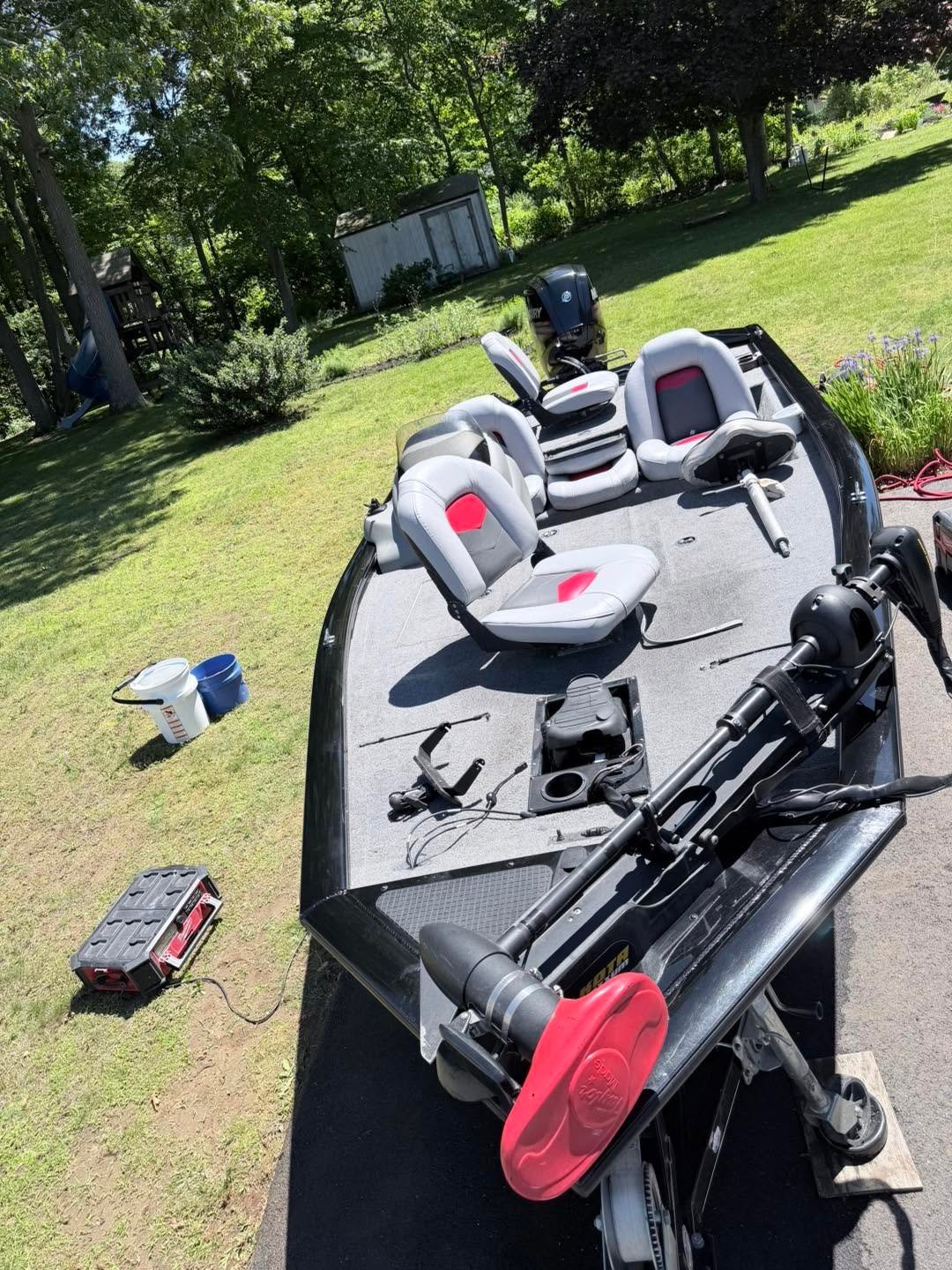 Overhead view of a white and red fishing boat with motor and seats, ready for detailing